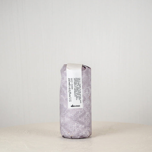 Silver cylindrical container with a label on a white surface and light gray background