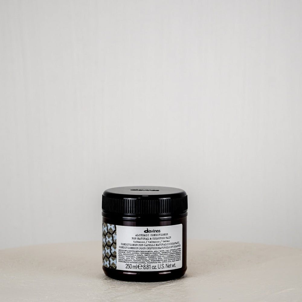 Black jar with a label on a white surface against a light gray background