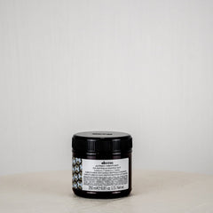 Black jar with a label on a white surface against a light gray background
