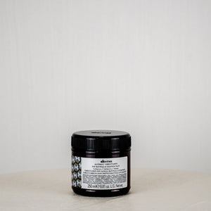 Black jar with a label on a white surface against a light gray background