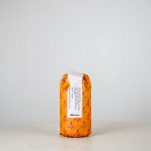 Orange hair product bottle with white label on a light gray background