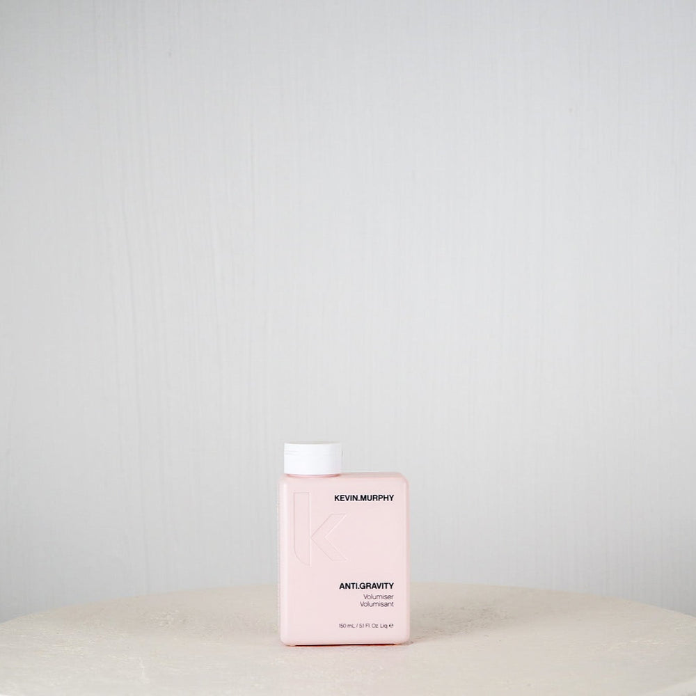 Pink bottle of Revlonmurphy hair product on a white surface with a light gray background