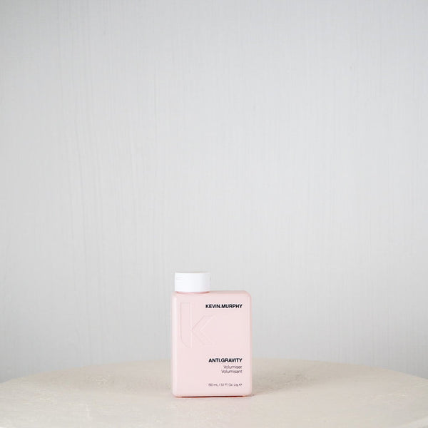 Pink bottle of Revlonmurphy hair product on a white surface with a light gray background