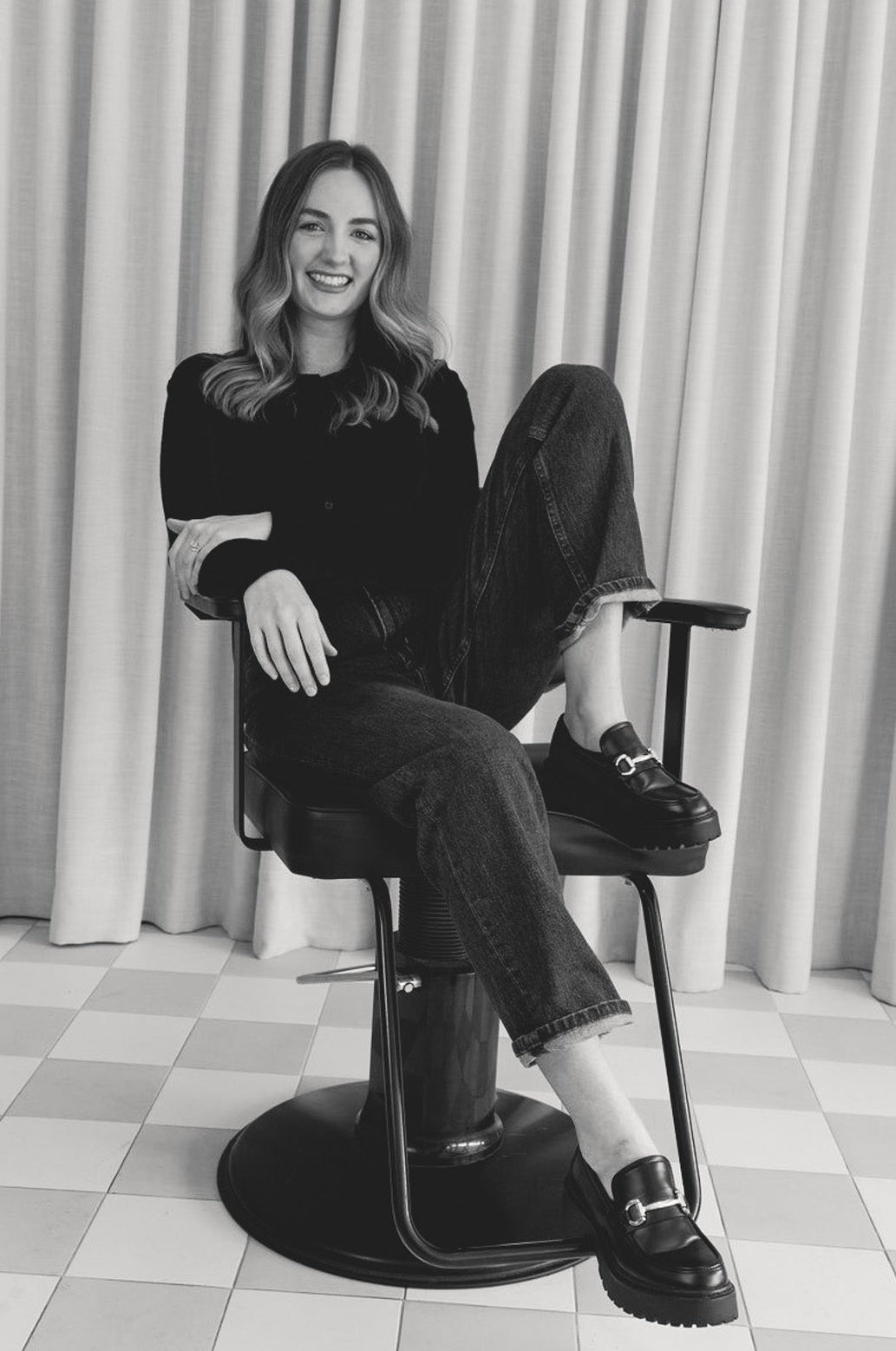 Woman sitting on a chair in a room with checkered floor and curtains