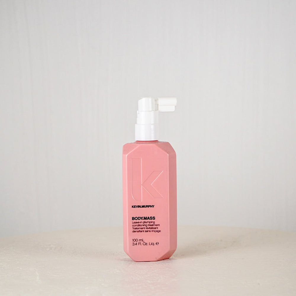 Pink bottle of Kevin Murphy product on a white surface with a light gray background