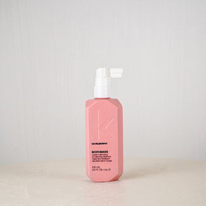 Pink bottle of Kevin Murphy product on a white surface with a light gray background