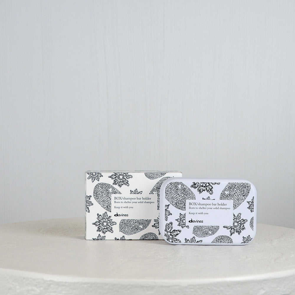 Shampoo bar and holder packaging with floral design on a white surface and light gray background