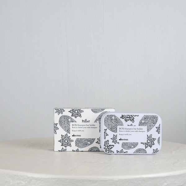 Shampoo bar and holder packaging with floral design on a white surface and light gray background