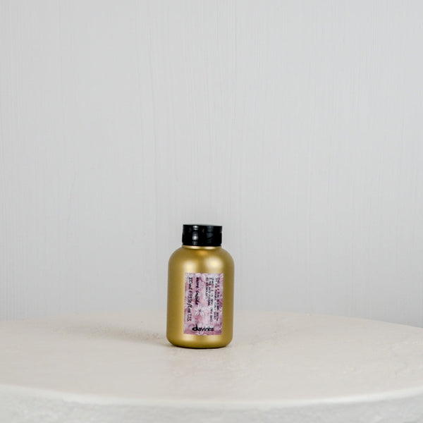 Gold bottle with black cap on a white surface and light gray background