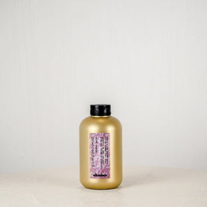 Gold bottle with black cap on a white surface against a light gray background