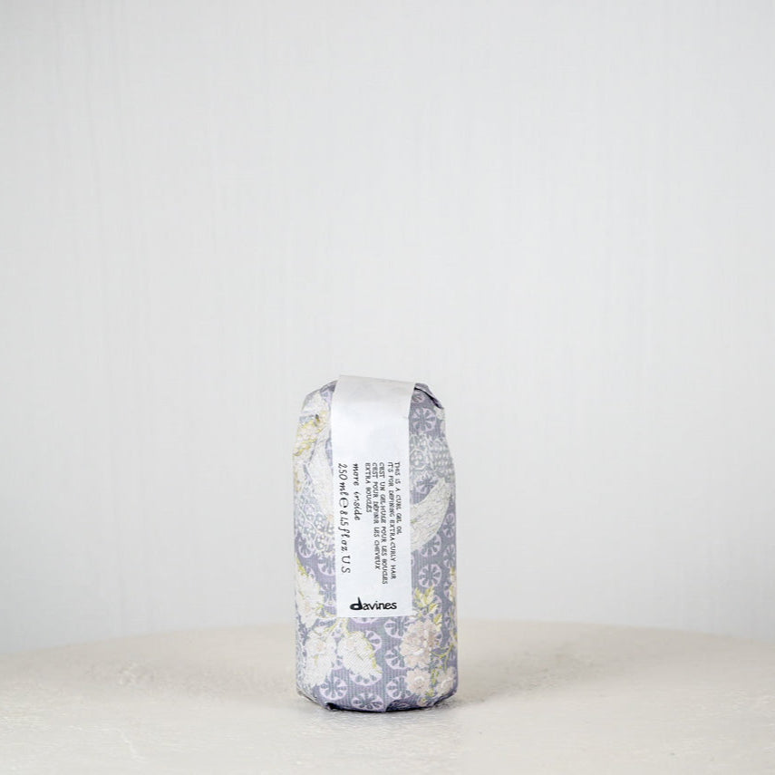 Hair product container with floral design and 'devines' branding on a white background