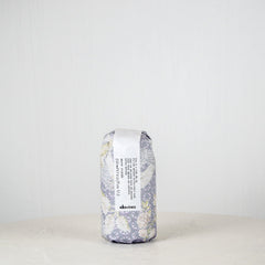 Hair product container with floral design and 'devines' branding on a white background