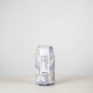 Hair product container with floral design and 'devines' branding on a white background