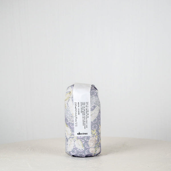 Hair product container with floral design and 'devines' branding on a white background