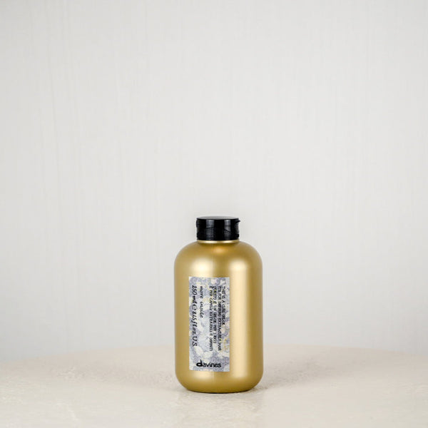 Gold bottle with black cap on a white surface against a light gray background