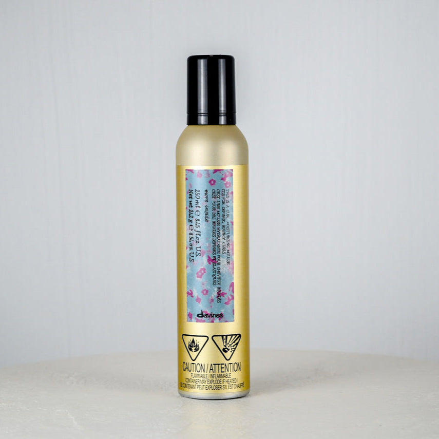 Hair product bottle with floral label on a light gray background