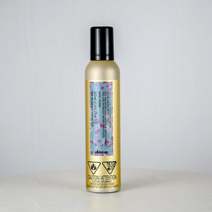 Hair product bottle with floral label on a light gray background