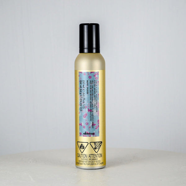 Hair product bottle with floral label on a light gray background