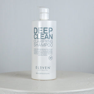 Bottle of Eleven Deep Clean Clarifying Shampoo on a white surface with a gray background
