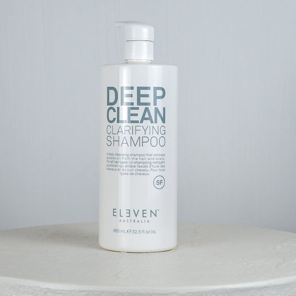 Bottle of Eleven Deep Clean Clarifying Shampoo on a white surface with a gray background