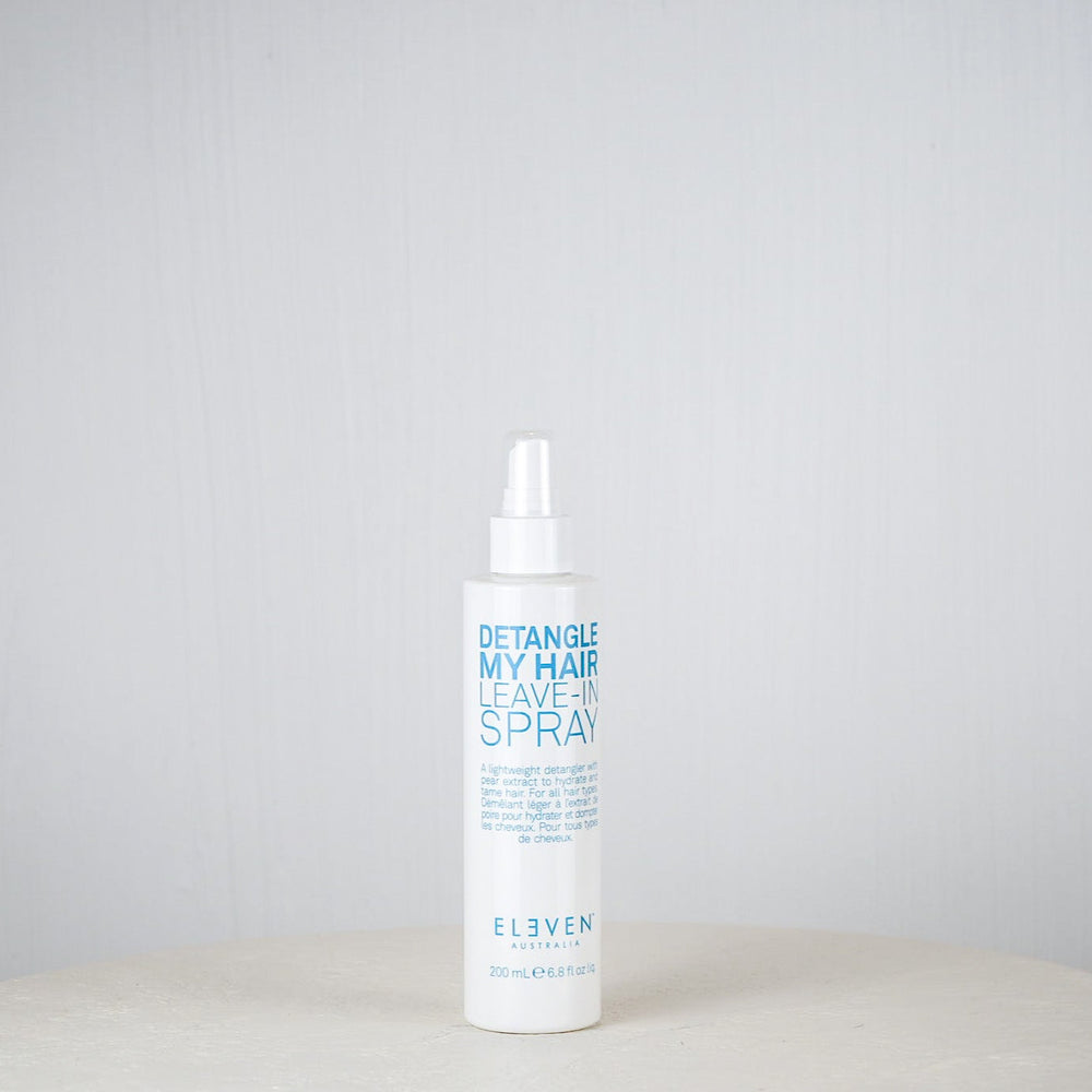 Bottle of 'Eleven' hair care product on a white surface with a gray background