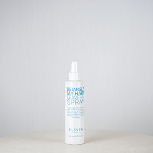 Bottle of 'Eleven' hair care product on a white surface with a gray background