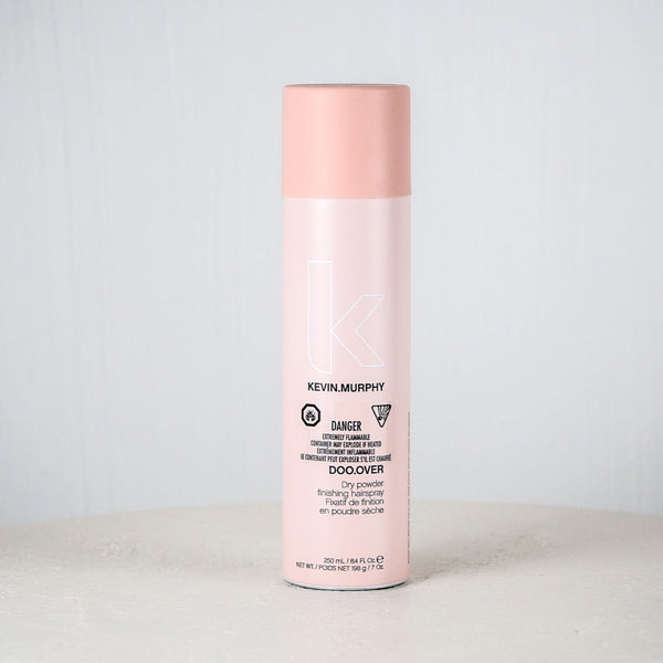 Pink bottle of Kevin Murphy product on a white surface with a white background