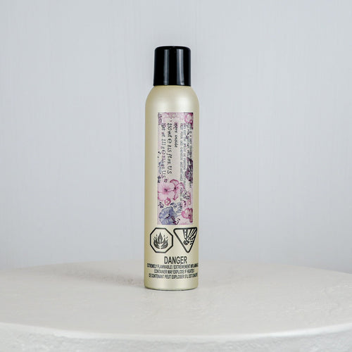Hair product bottle with floral label on a white surface
