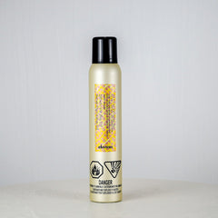 Hair product spray bottle with a black cap on a light gray background