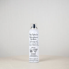 White bottle with black text on a white surface against a light gray background