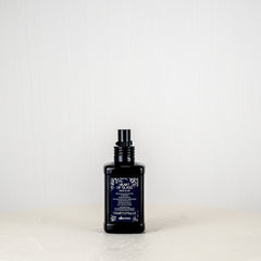 Black bottle with purple label on a white surface and light gray background