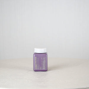 Purple container with white cap on a white surface and light gray background