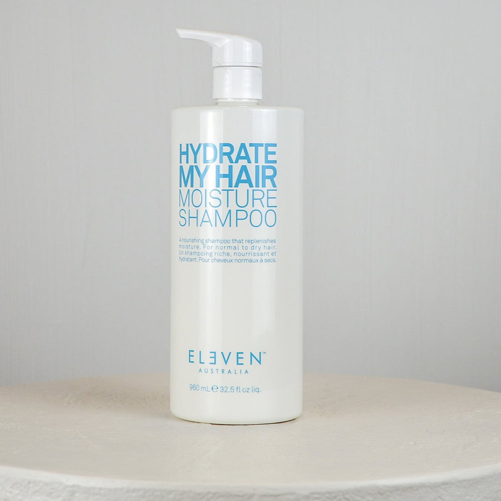 Shampoo bottle labeled 'Hydrate My Hair Moisture Shampoo' by 'Eleven' on a gray background