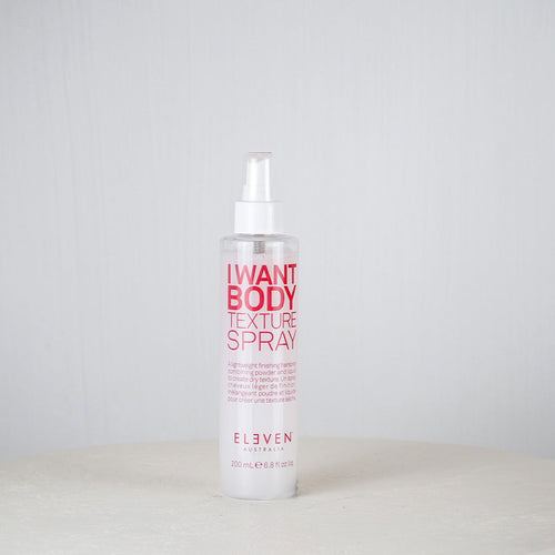 Bottle of 'I Want Body Texture Spray' by Eleven on a white surface with a light gray background