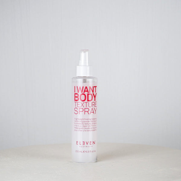 Bottle of 'I Want Body Texture Spray' by Eleven on a white surface with a light gray background