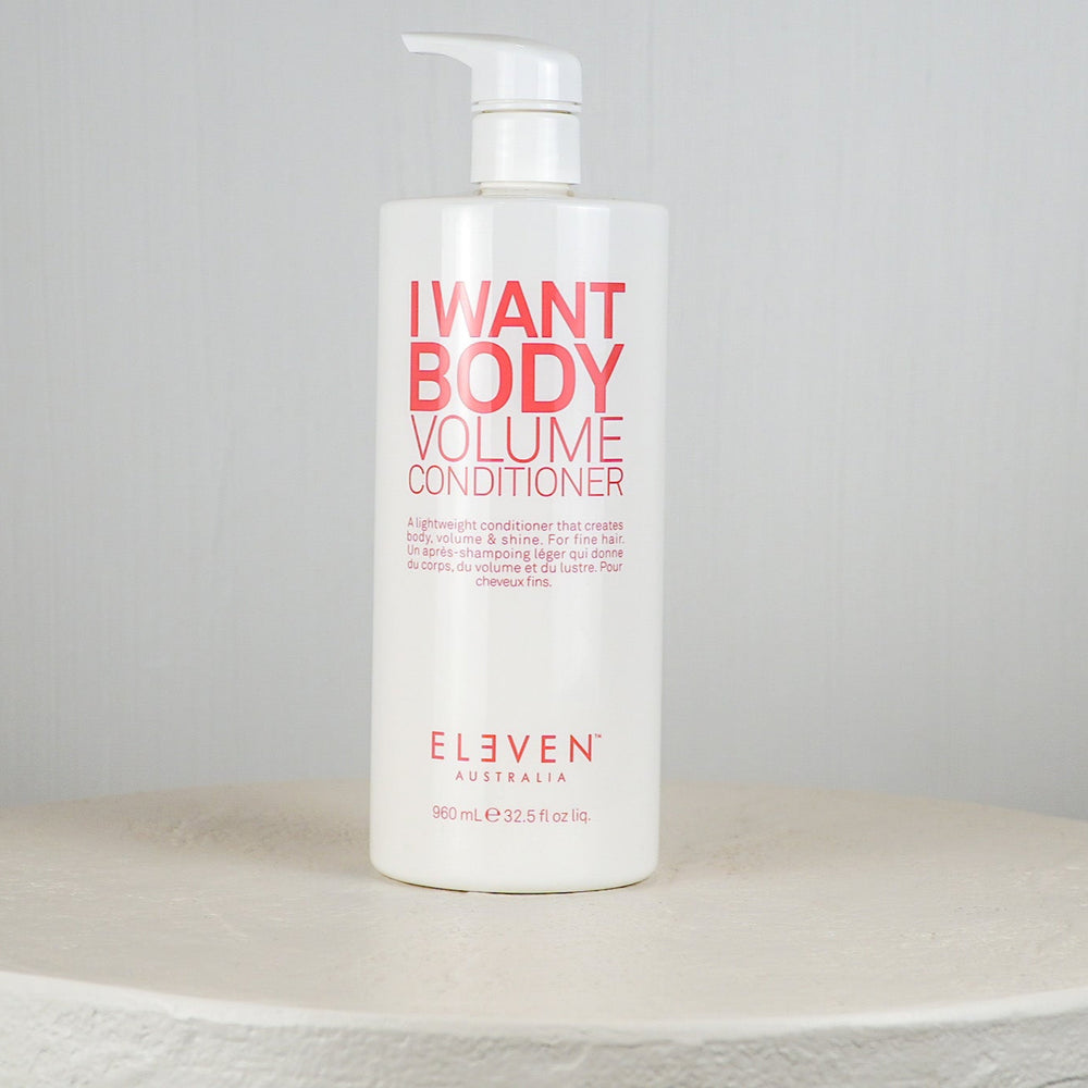 White bottle of 'I Want Body Volume Conditioner' by Eleven on a light gray background