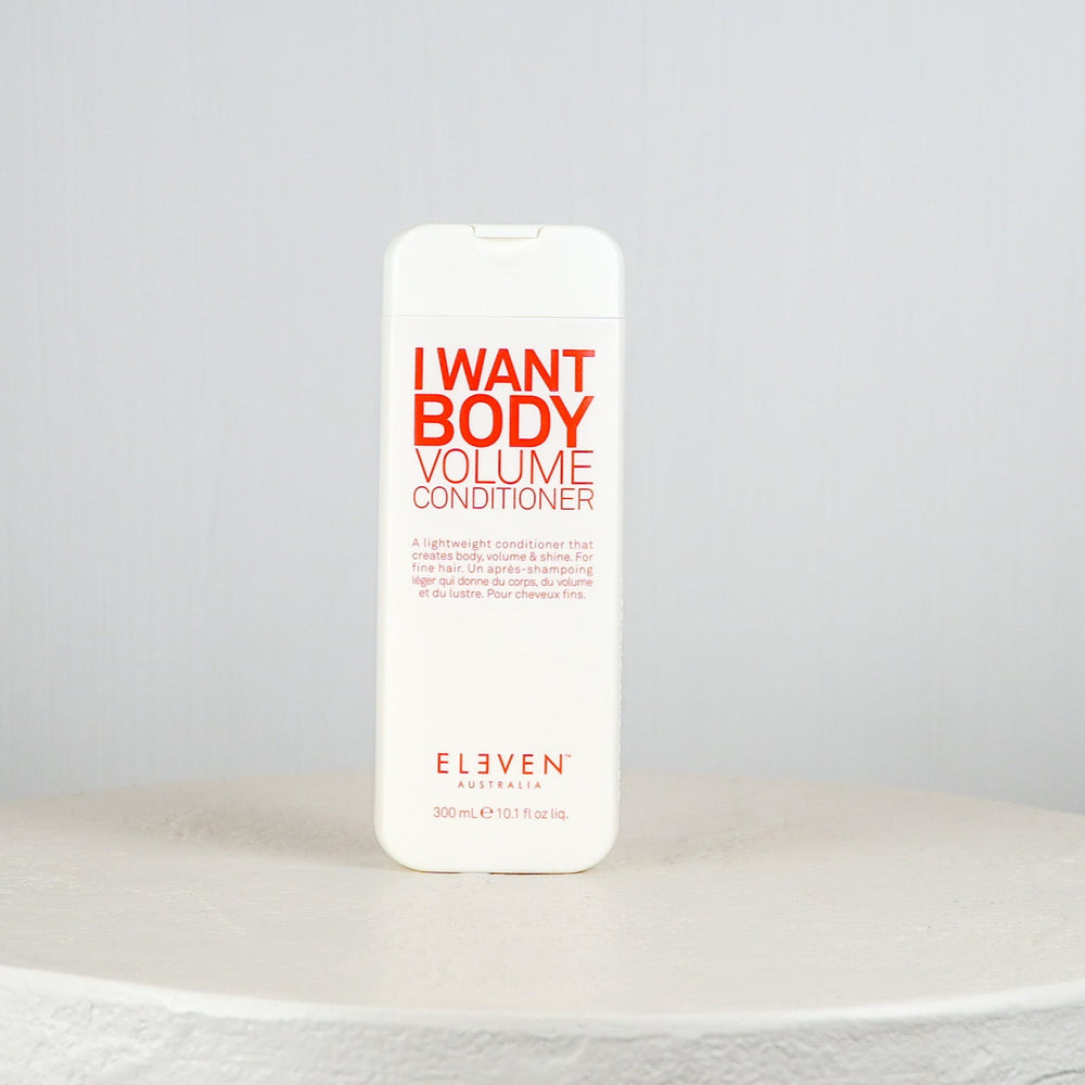 White bottle of 'I Want Body Volume Conditioner' by Eleven on a light gray background