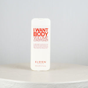 White bottle of 'I Want Body Volume Conditioner' by Eleven on a light gray background