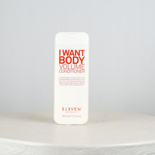 White bottle of 'I Want Body Volume Conditioner' by Eleven on a light gray background