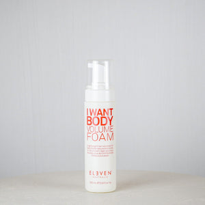 Bottle of 'I Want Body Volume Foam' by Eleven on a white surface with a gray background