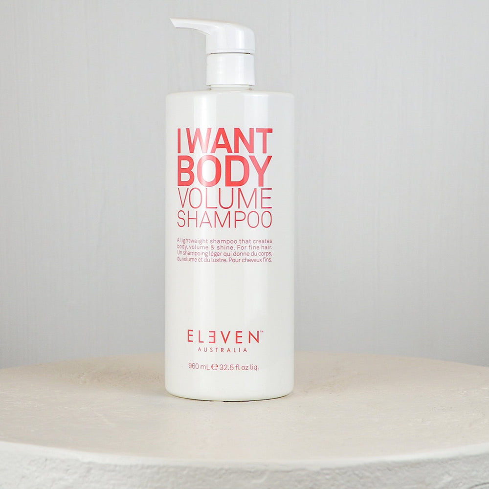 Shampoo bottle labeled 'I Want Body Volume Shampoo' by Eleven on a white surface with a gray background