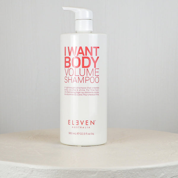 Bottle of 'I Want Body Volume Shampoo' by Eleven on a white surface with a gray background