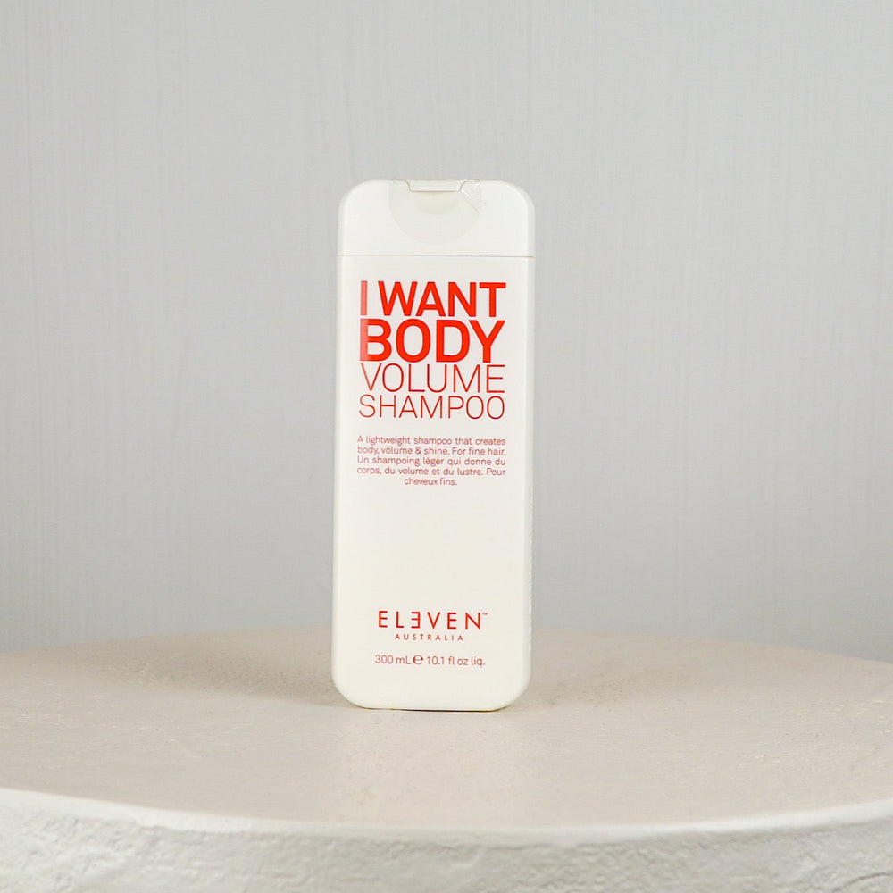 Shampoo bottle labeled 'I Want Body Volume Shampoo' by Eleven on a white surface with a gray background