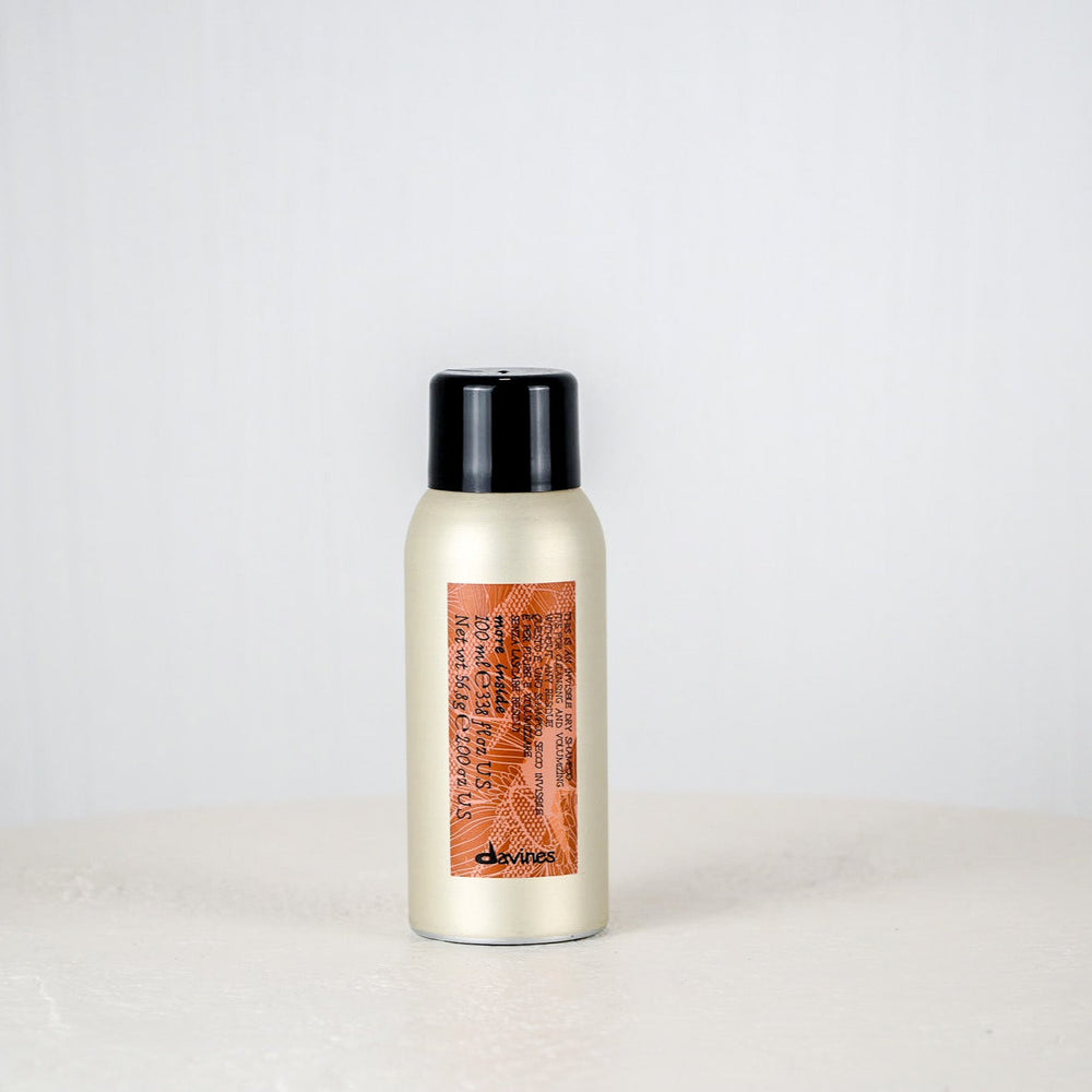 Bottle of hair product on a white surface with a gray background