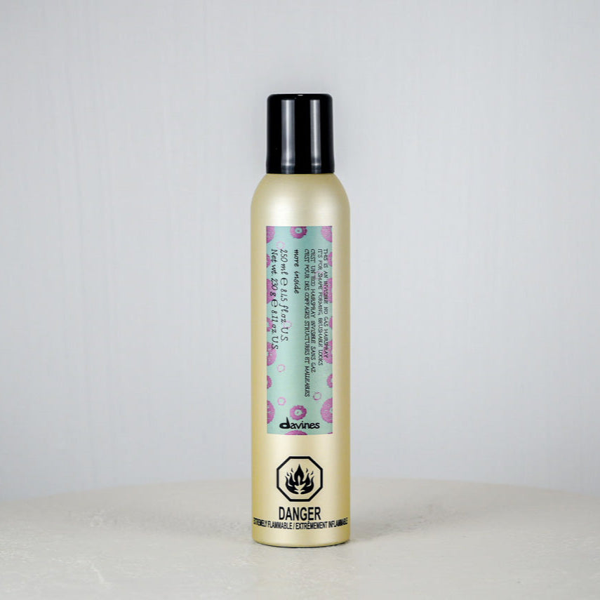 Hair product bottle with floral label on a light gray background