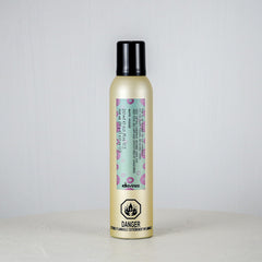 Hair product bottle with floral label on a light gray background