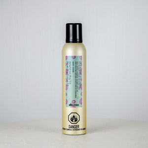 Hair product bottle with floral label on a light gray background