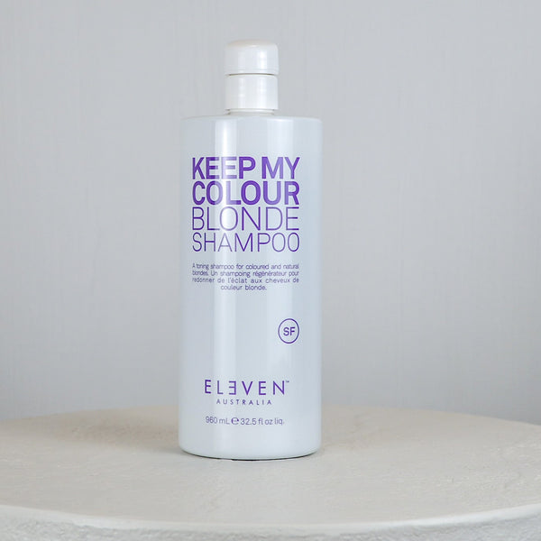 Bottle of 'Keep My Colour Blonde Shampoo' by Eleven on a white surface with a light gray background