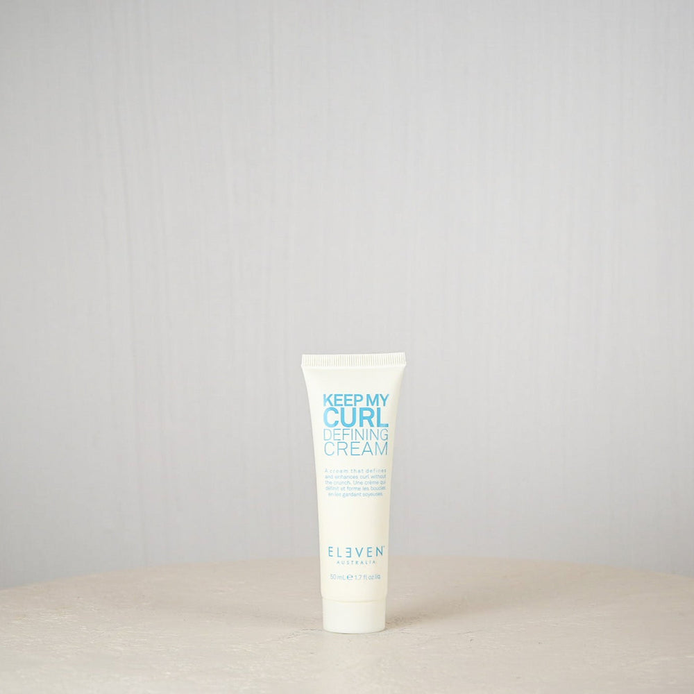Tube of 'Keep My Curl Defining Cream' by Eleven on a light gray background