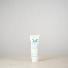 Tube of 'Keep My Curl Defining Cream' by Eleven on a light gray background